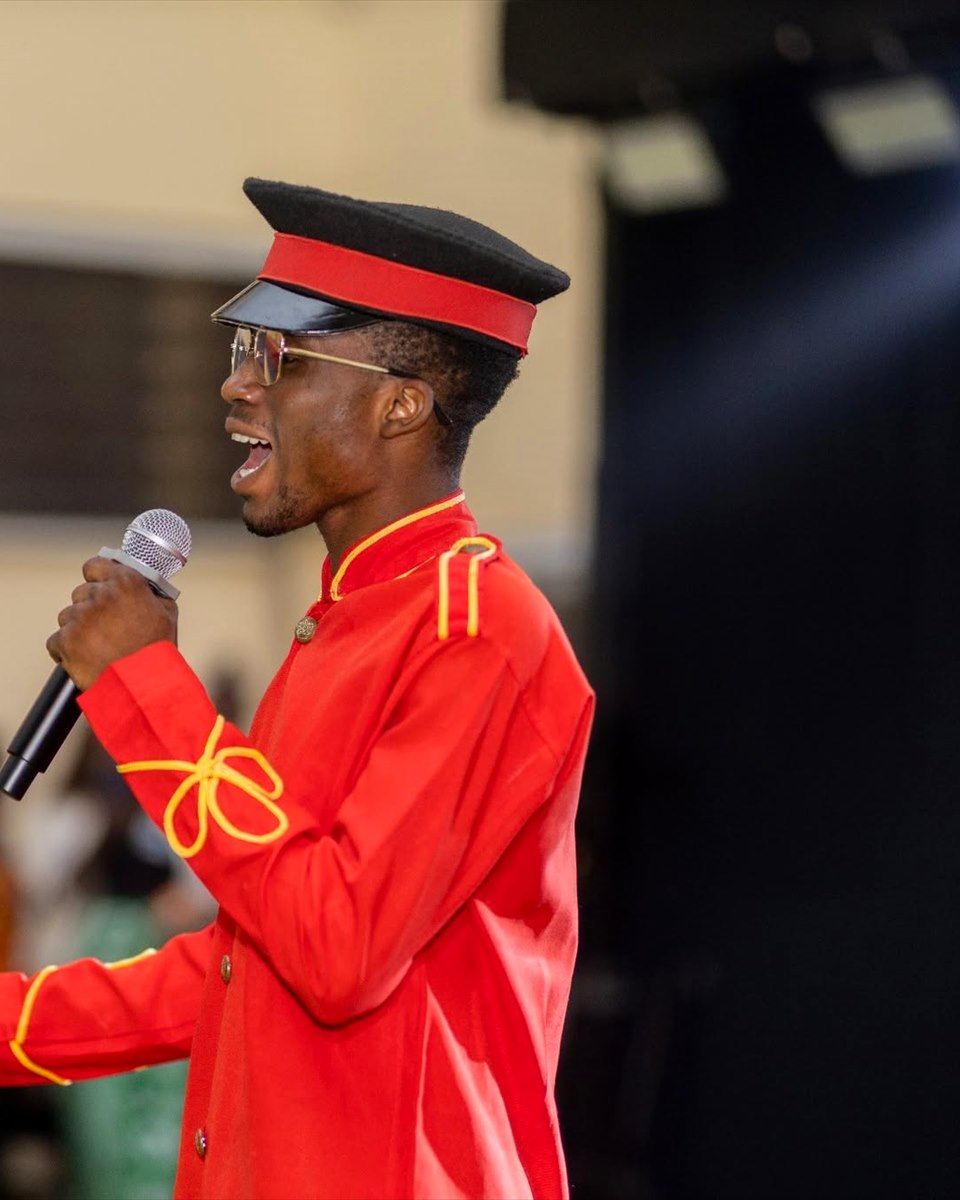 Francis Pwavwe speaking into a microphone in ceremonial uniform